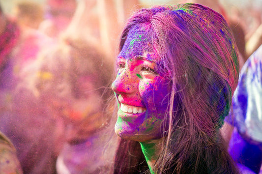 Woman smiling and covered in colorful Holi powder at a color run event