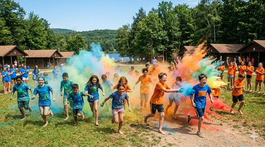 Summer camp color war event with kids in colored team shirts competing through colorful powder explosions