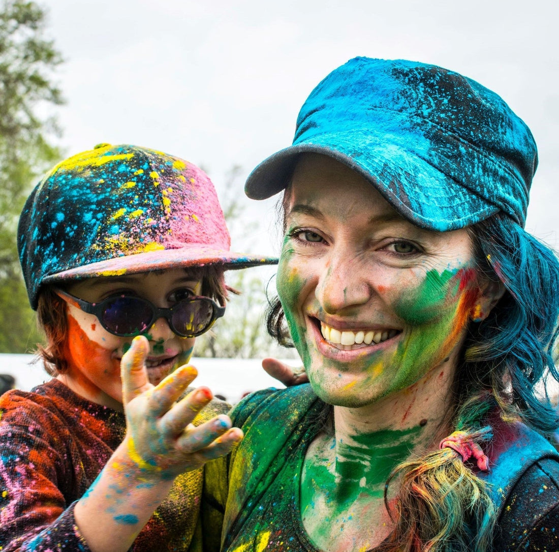 Mother and child smiling and covered in colorful powder at a color powder fun run event